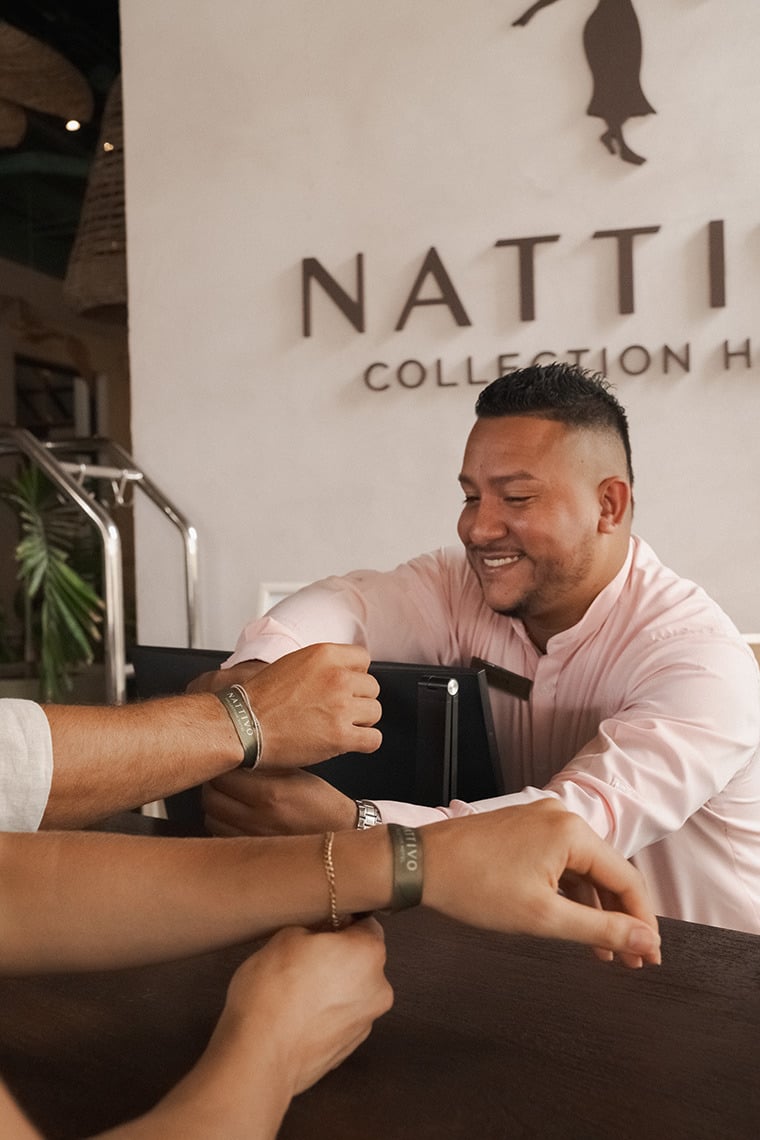 Happy guests wearing NATIVO Nattivo Collection Hotel wristbands at a hotel reception.