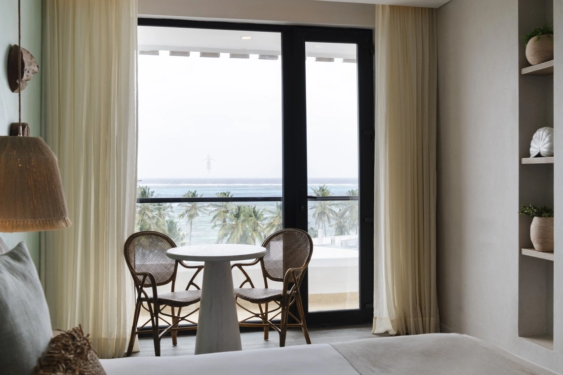 Vista da varanda de quarto de hotel com vista para o mar e coqueiros. Nattivo Collection Hotel