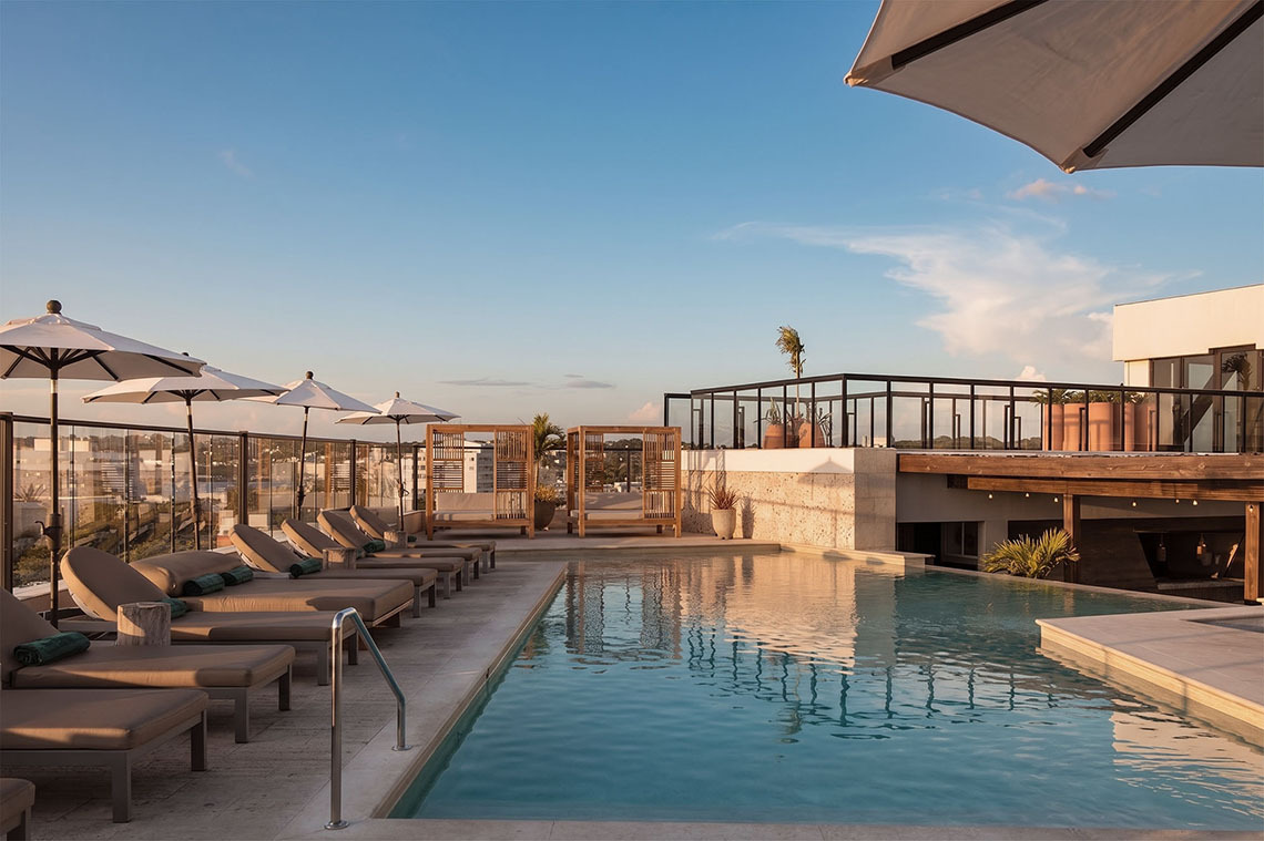 Piscina de rooftop com espreguiçadeiras e guarda-sóis em um hotel Nattivo Collection Hotel