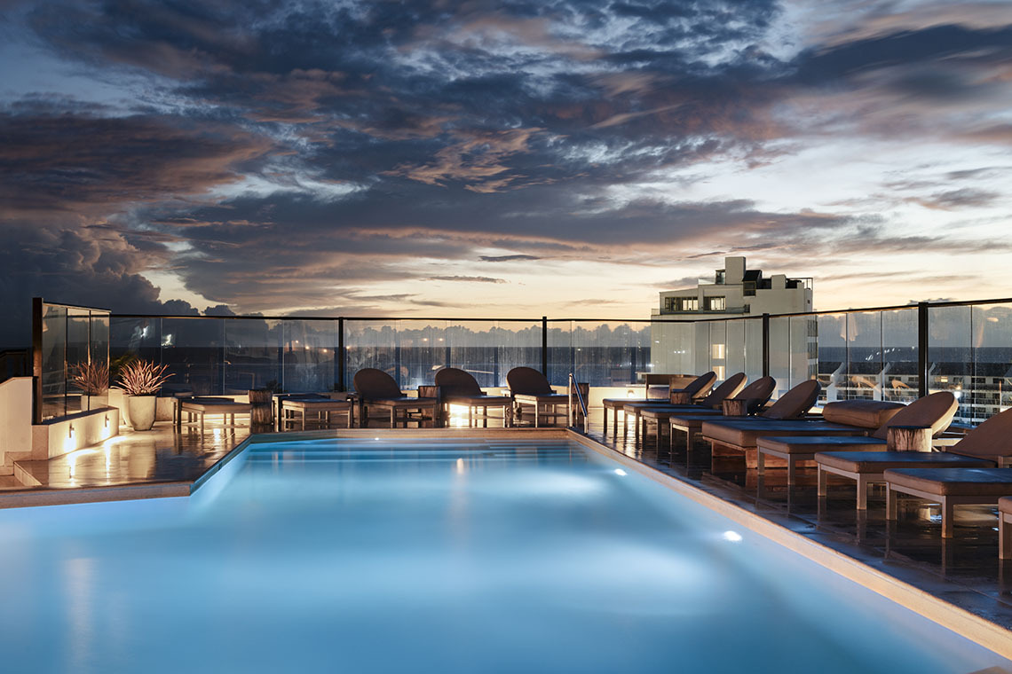 Piscina en la azotea Nattivo Collection Hotel con tumbonas al atardecer.