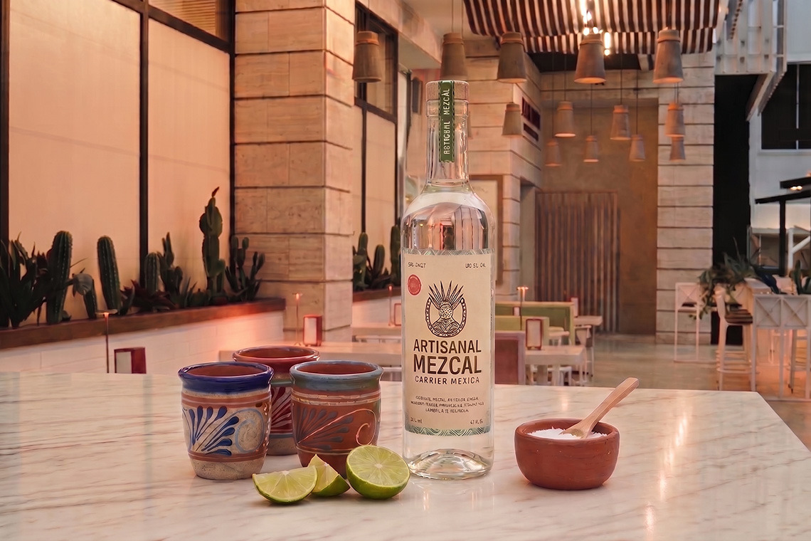 Mezcal artesanal com copos e limas para uma noite de Nattivo Collection Hotel em um restaurante mexicano.