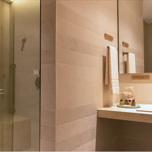 Baño moderno con ducha de cristal, lavabo y toallas. Nattivo Collection Hotel