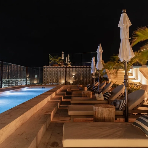 Piscina en azotea de hotel de lujo con tumbonas y vista nocturna de la ciudad Nattivo Collection Hotel