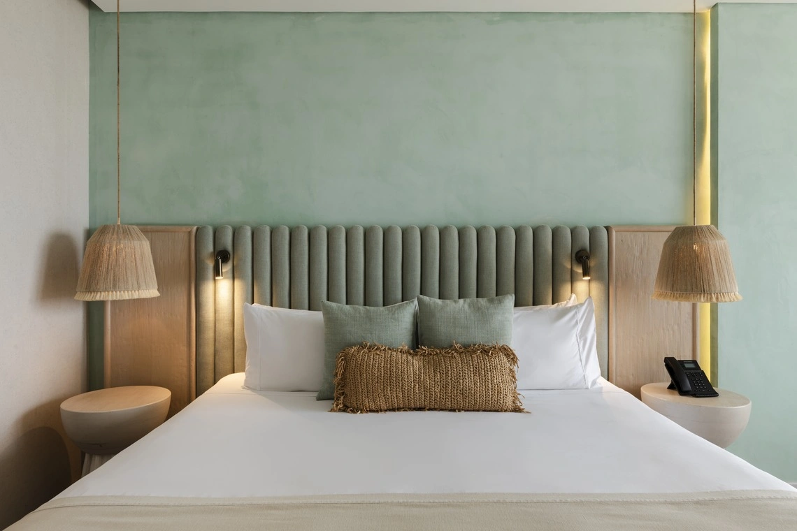 Cama confortável em quarto de hotel comNattivo Collection Hotel, pendentes e almofadas decorativas.