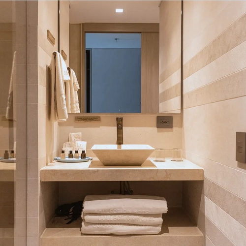 Baño de lujo en Nattivo Collection Hotel con lavabo cuadrado, toallas blancas y secador.