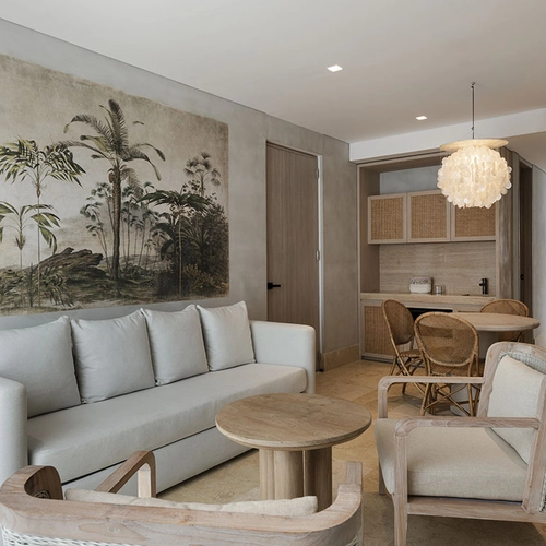 Espacio de estar tropical con sofá Nattivo Collection Hotel, sillas de mimbre y arte mural botánico.