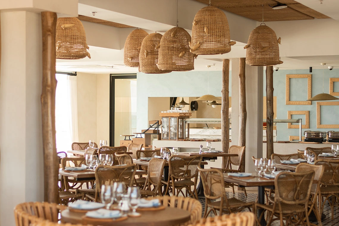 Ambiente elegante em hotel com mesas postas e cadeiras de vime, ideal para experiências gastronômicas Nattivo Collection Hotel.