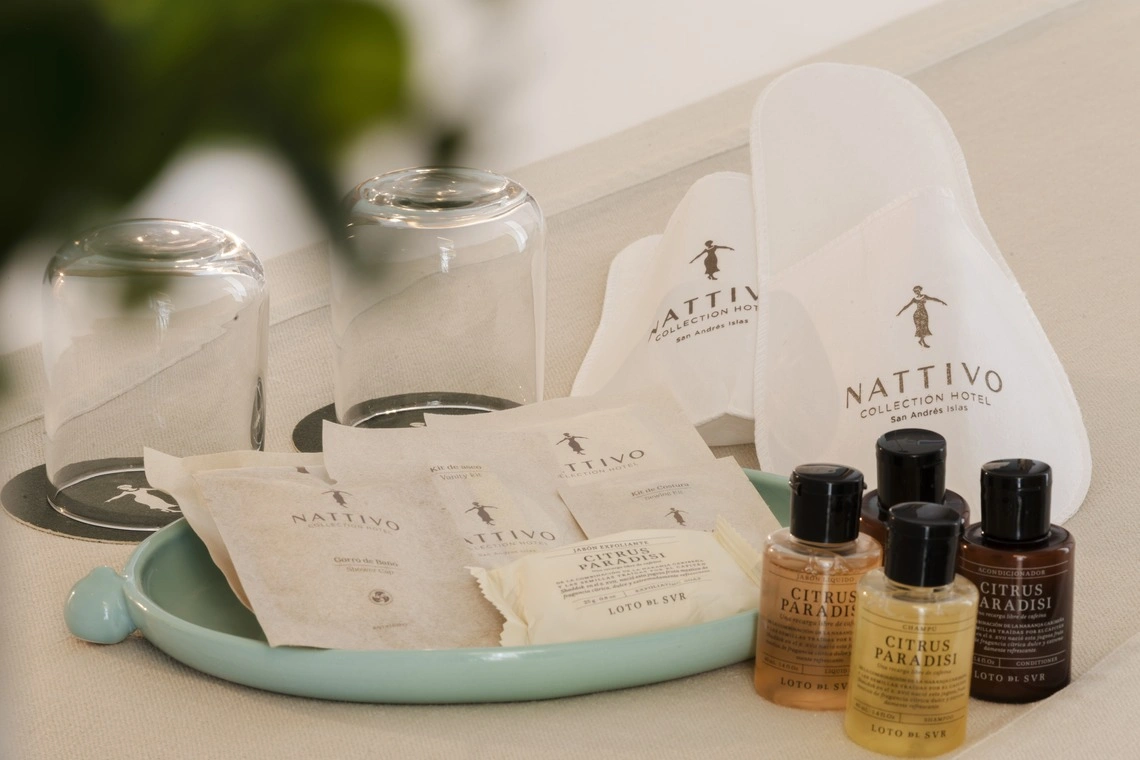 Amenidades de hotel 'Nattivo Collection Hotel' com chinelos, sabonetes e produtos de higiene pessoal.