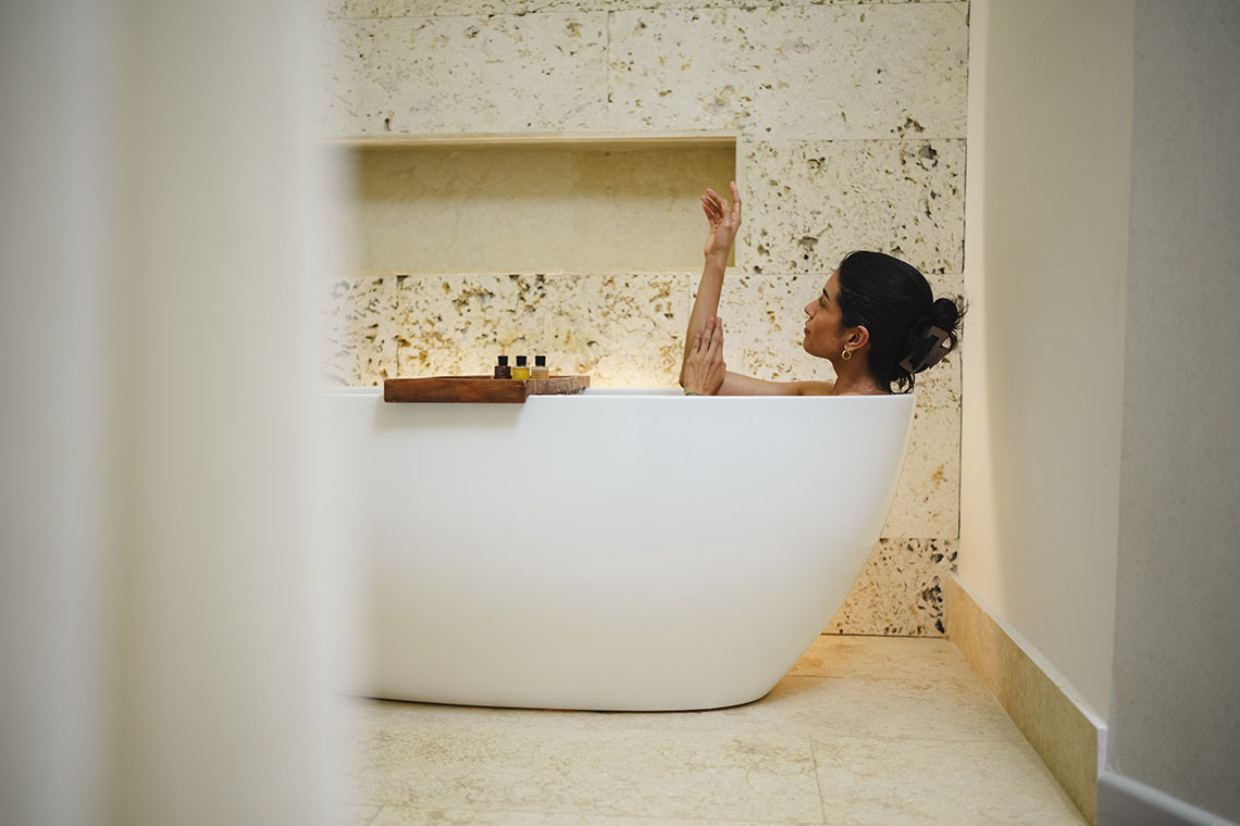 Mulher relaxa em banheira Nattivo Collection Hotel.