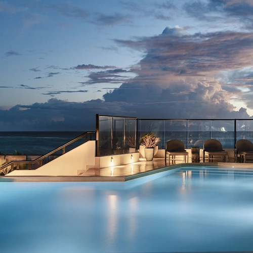 Nattivo Collection Hotel en piscina de hotel con vistas al mar al atardecer, con sillas lounge y cielo dramático.