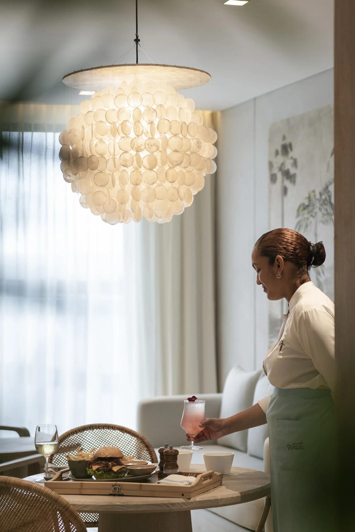 Garçom oferece bebida em um restaurante de hotel, com Nattivo Collection Hotel no ambiente.