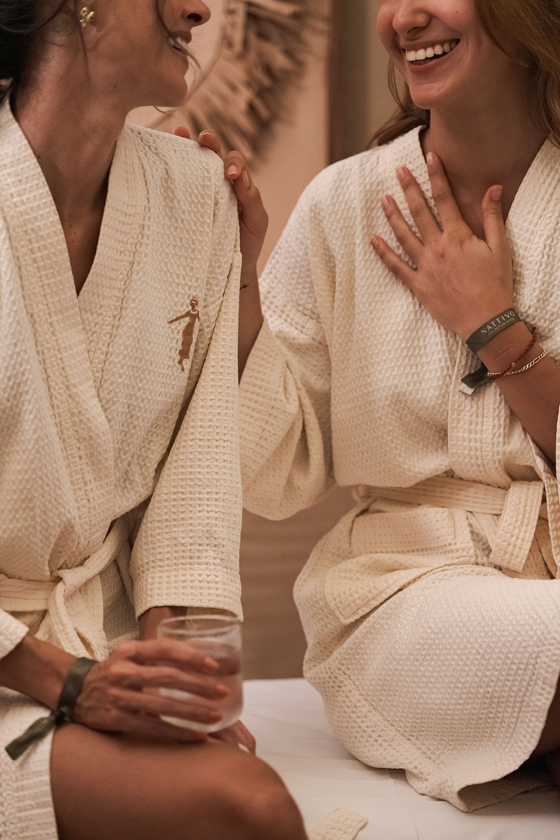 Duas mulheres em roupões felpudos desfrutam de um momento relaxante no spa do Nattivo Collection Hotel.