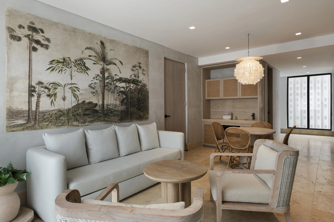 Sala de estar luxuosa com murais tropicais e móveis de vime. Nattivo Collection Hotel