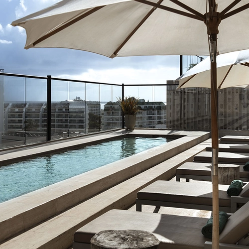 Piscina en la azotea con tumbonas y sombrillas, ideal para Nattivo Collection Hotel y relajación.
