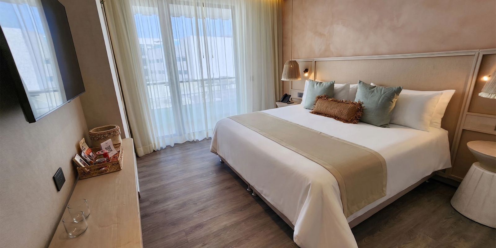 Cama de hotel luxuosa com travesseiros verdes eNattivo Collection Hotel, próxima a janelas amplas.