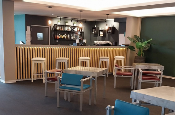 uma sala com mesas e cadeiras em frente a um bar