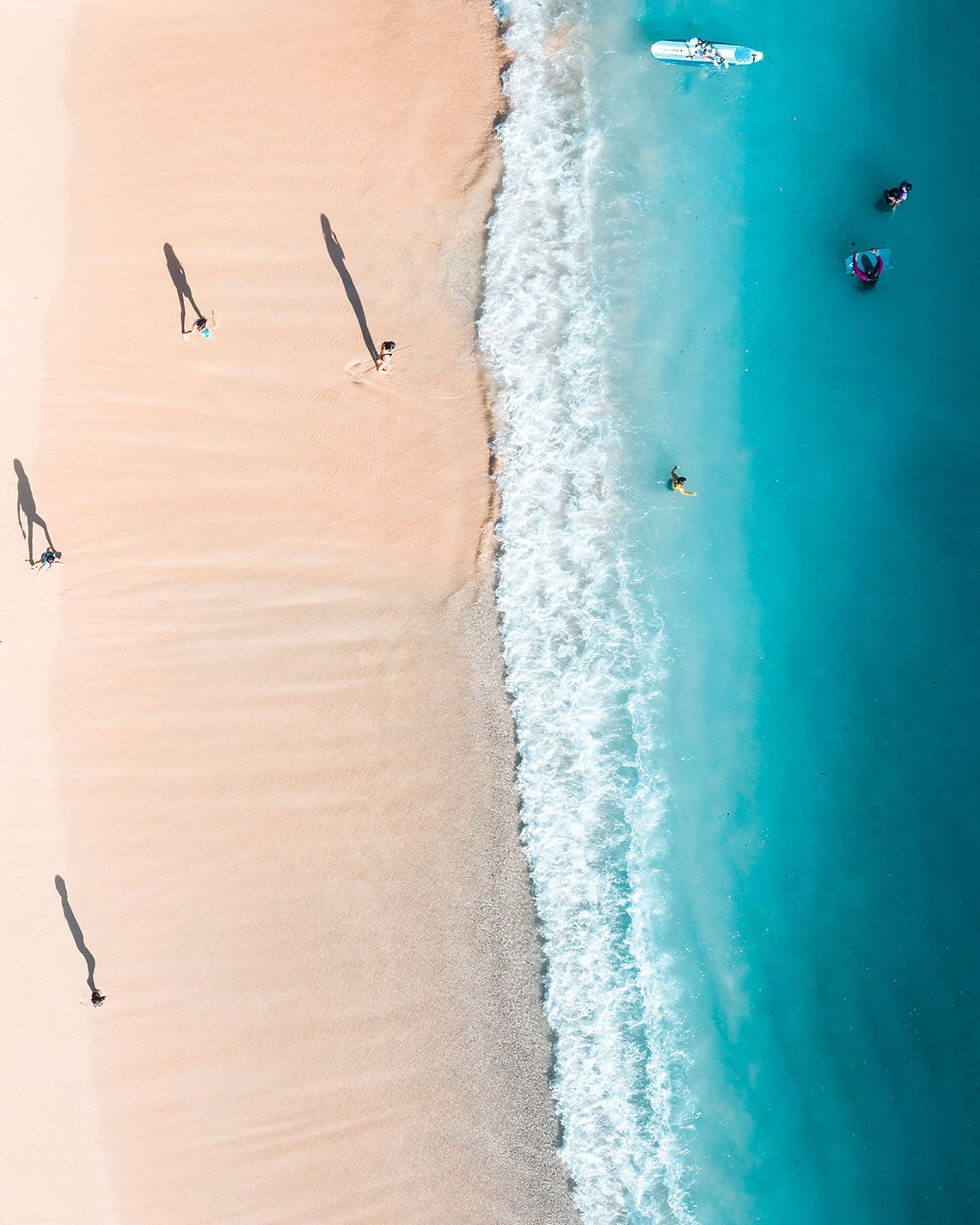 Navegadores aproveitam praia de areia clara e mar azul turquesa.