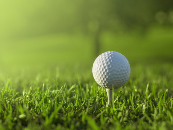 Ein Mann schlägt einen Golfball mit einem Club auf einem Golfplatz .