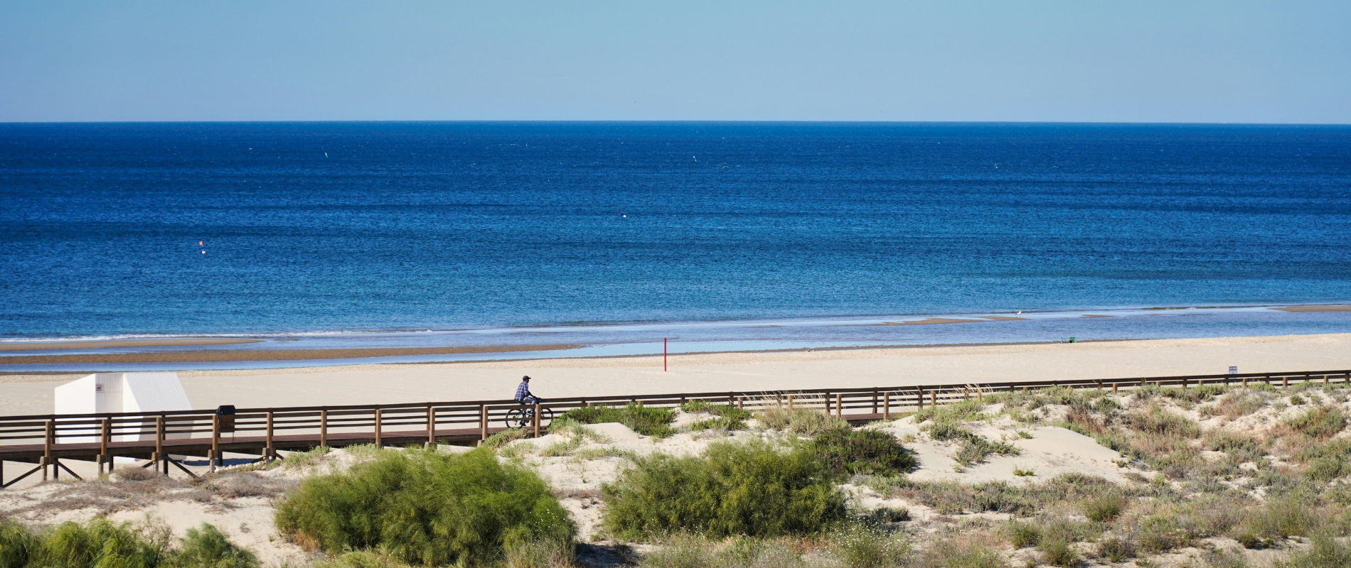 a man riding a bike on a boardwalk overlooking the ocean