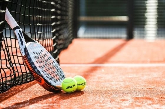 une raquette de tennis et deux balles de tennis sont assises sur un court de tennis .