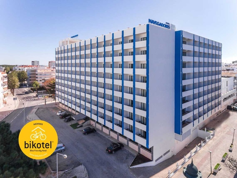 Uma vista aérea mostra o Hotel Navegadores, um edifício azul e branco, com um banner promocional de 