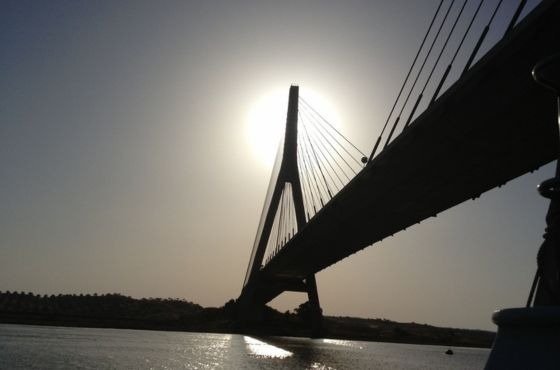 de zon schijnt door een brug over een rivier