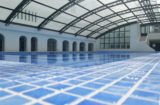 ein Schwimmbad mit blauen Fliesen und einem Glasdach