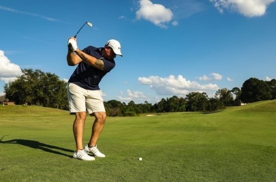 um homem está batendo uma bola de golfe em um campo de golfe .