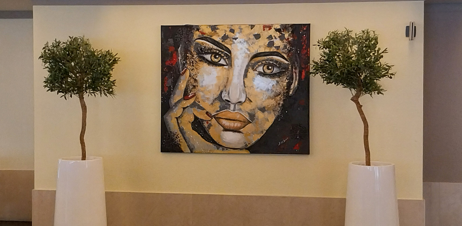 uma pintura de uma mulher está pendurada na parede ao lado de duas plantas
