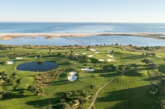 an aerial view of a golf course with the ocean in the background