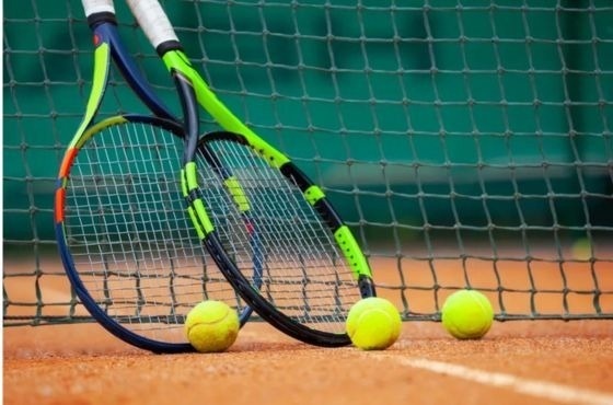 deux raquettes de tennis et trois balles de tennis sur un court de tennis .