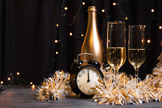 une bouteille de champagne est assise à côté d' un réveil et de deux verres de champagne