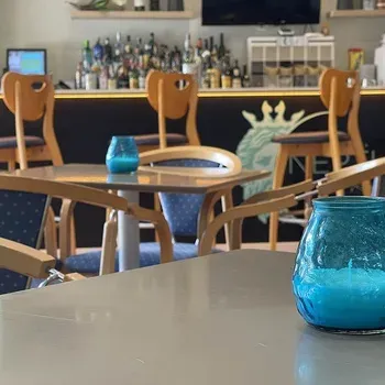 Blue candle on table at Hotel Neptuno. Wooden tables and chairs with blue cushions.