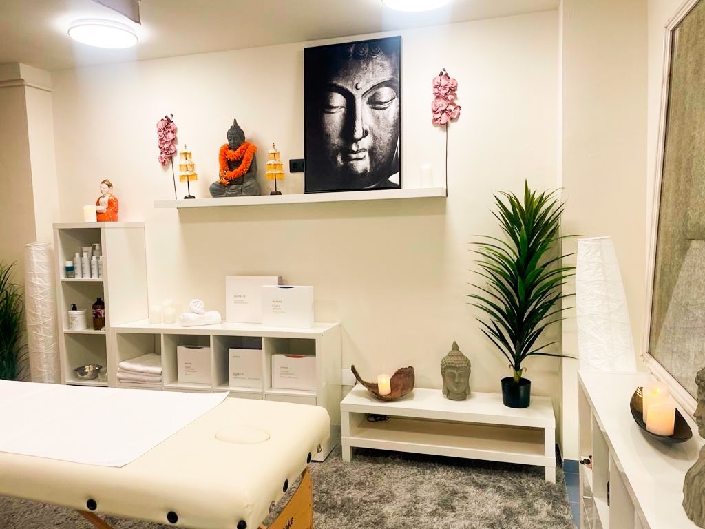 una habitación con una mesa de masaje y un cuadro de buda en la pared