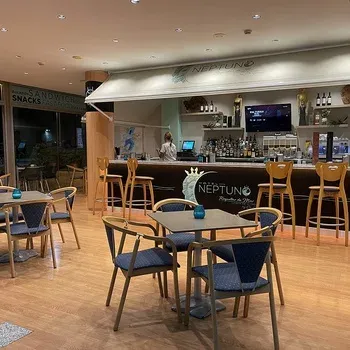 Hotel Neptuno's restaurant and bar, featuring wooden tables and chairs, a welcoming atmosphere.