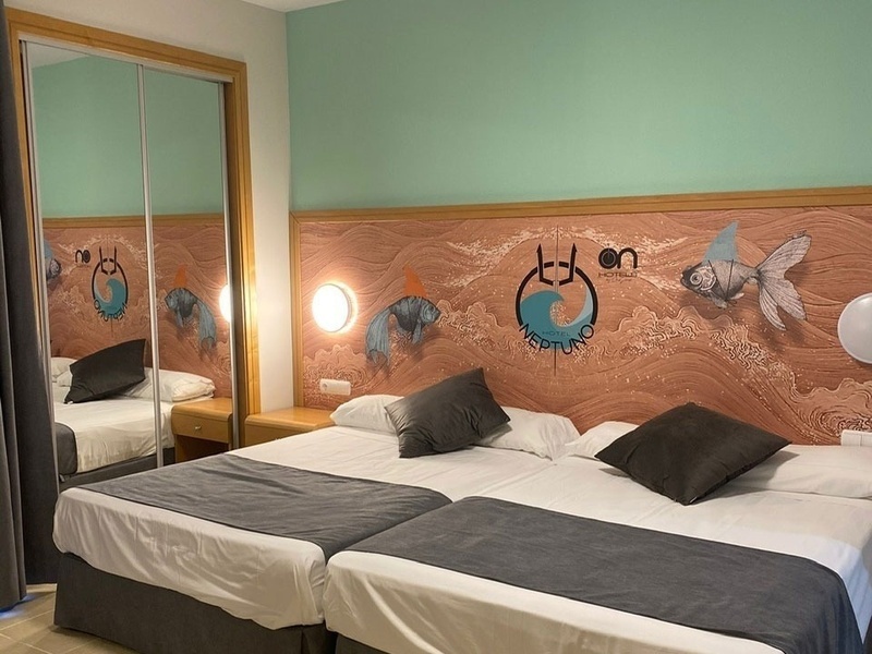 a hotel room with two beds and a mural on the wall that says 