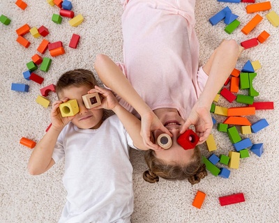 un niño y una niña juegan con bloques de madera en el suelo