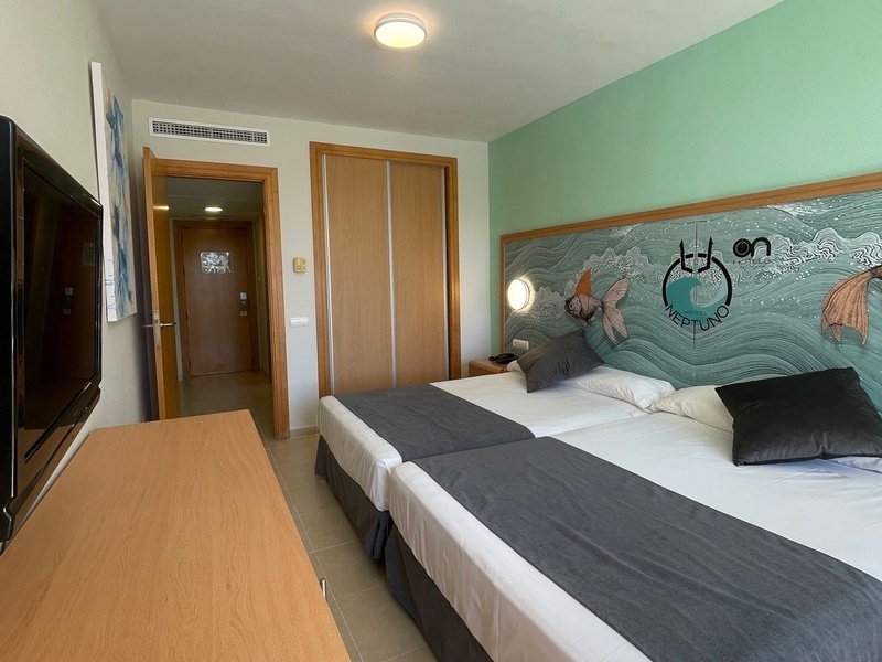 a hotel room with two beds and a painting on the wall that says ' reefland '