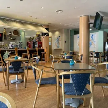 On Hotels: Neptuno lounge with blue tables, chairs, bar, and TV.