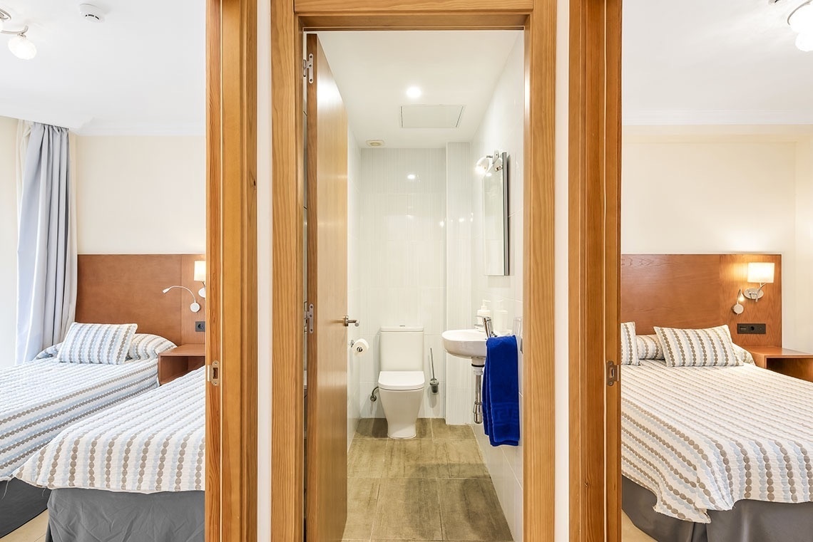 ein Schlafzimmer mit zwei Betten und einem Badezimmer mit Toilette und Waschbecken