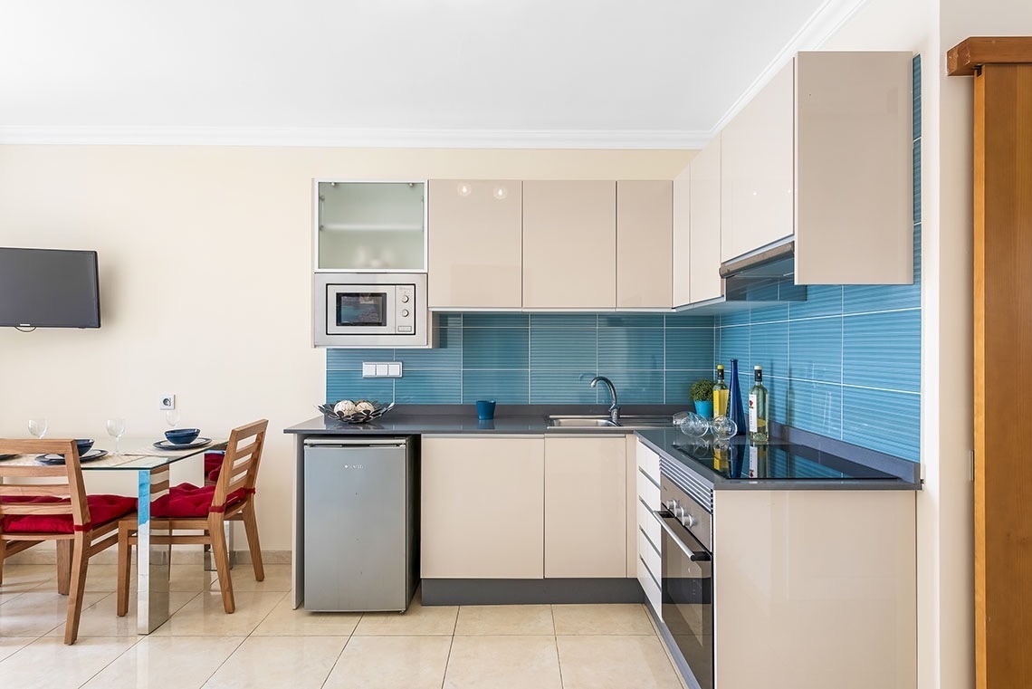 eine Küche mit weißen Schränken und blauen Fliesen