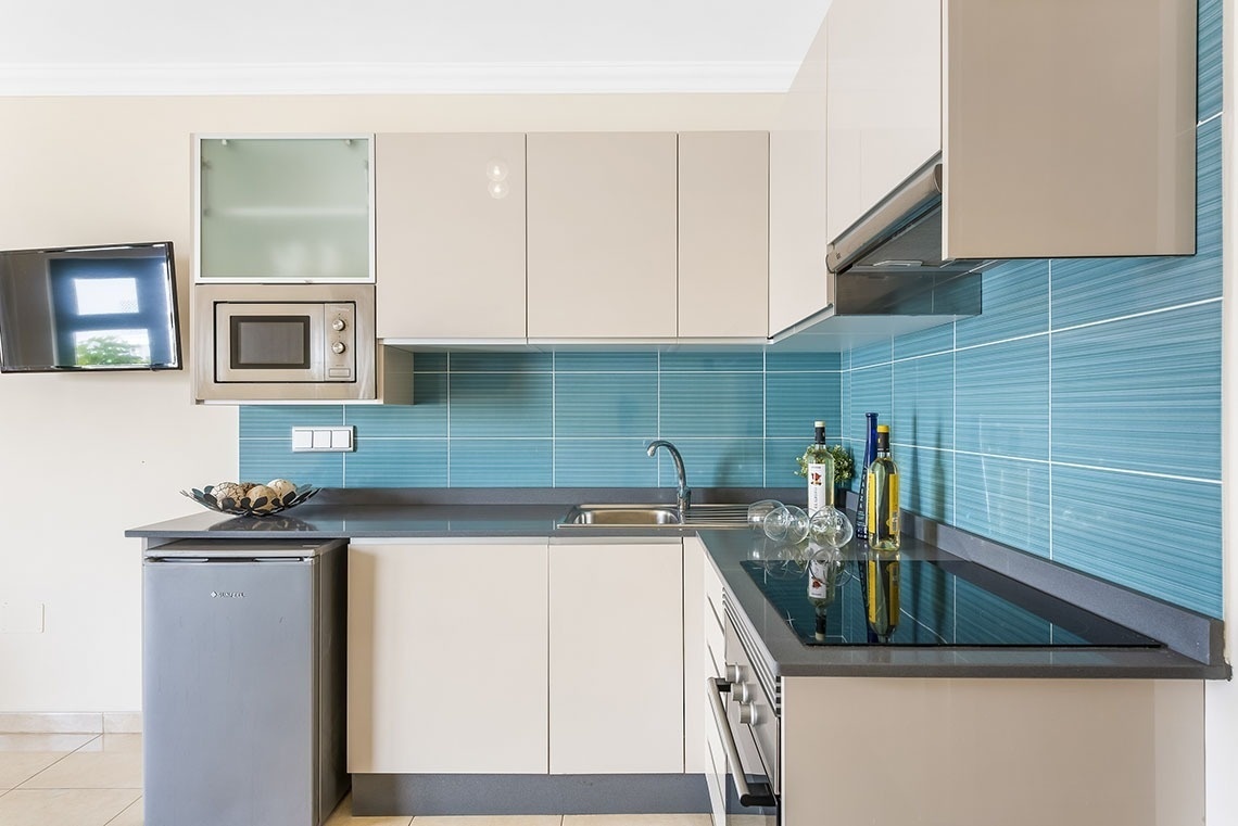 eine Küche mit blauen Fliesen und weißen Schränken