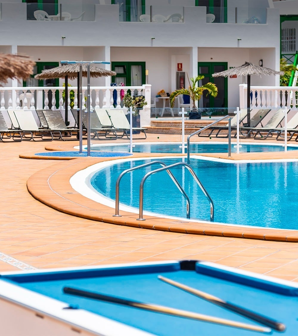 una piscina circondata da sedie e un amaca con un tramonto sullo sfondo