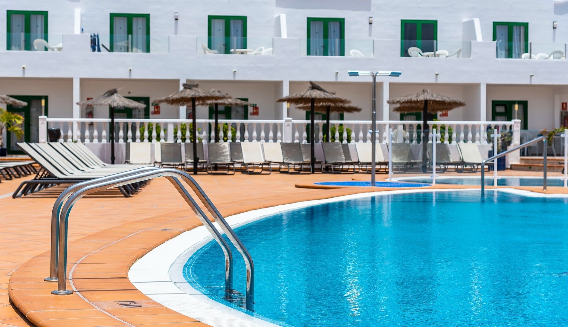 une piscine avec un lit à baldaquin et des palmiers en arrière-plan