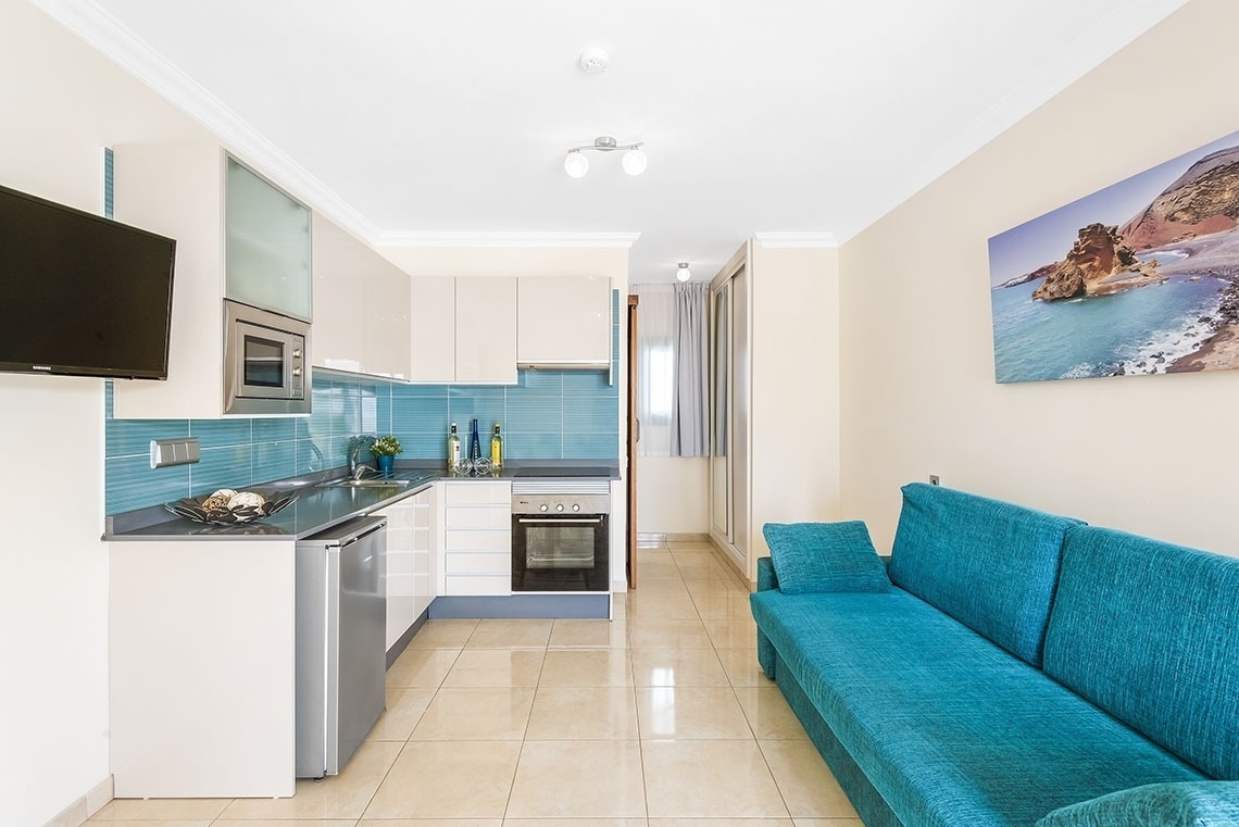 eine blaue Couch steht in einem Wohnzimmer neben einer Küche