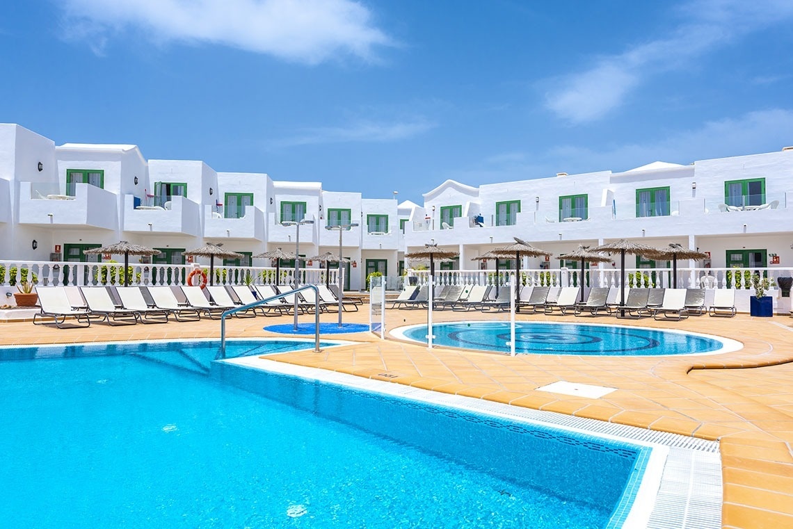 a large swimming pool surrounded by white chairs and umbrellas