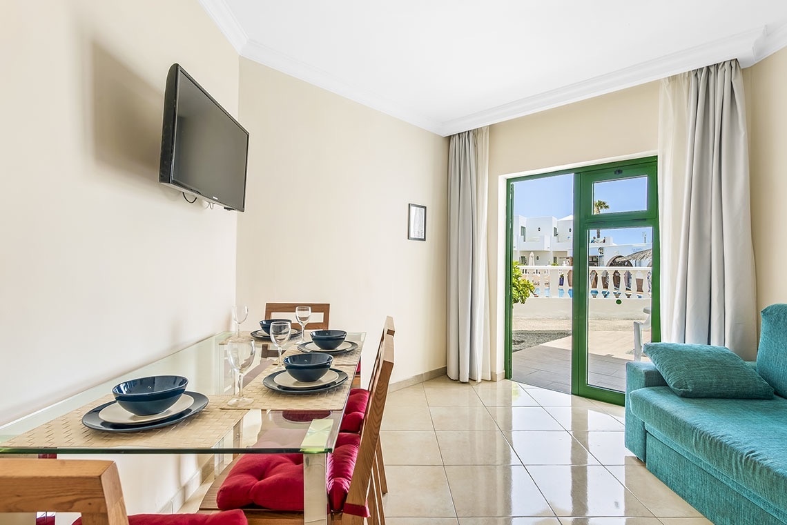 ein Wohnzimmer mit einem Tisch und Stühlen und einem Fernseher