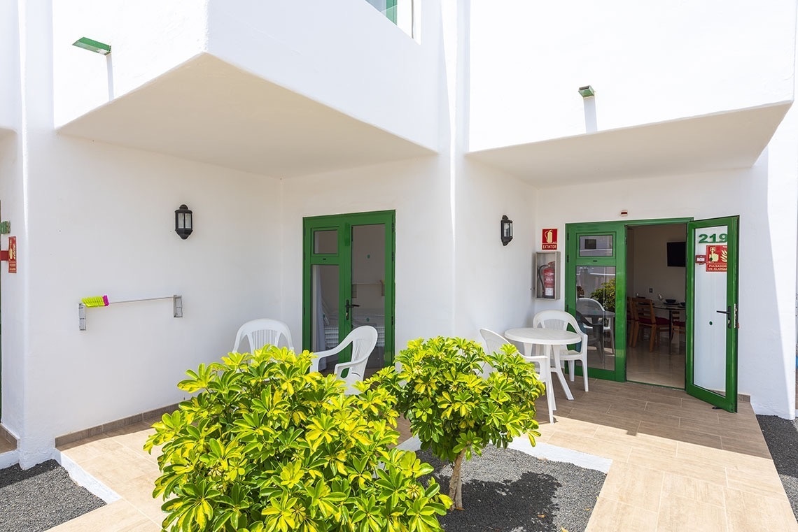 ein weißes Haus mit einer grünen Tür und einem Tisch und Stühlen