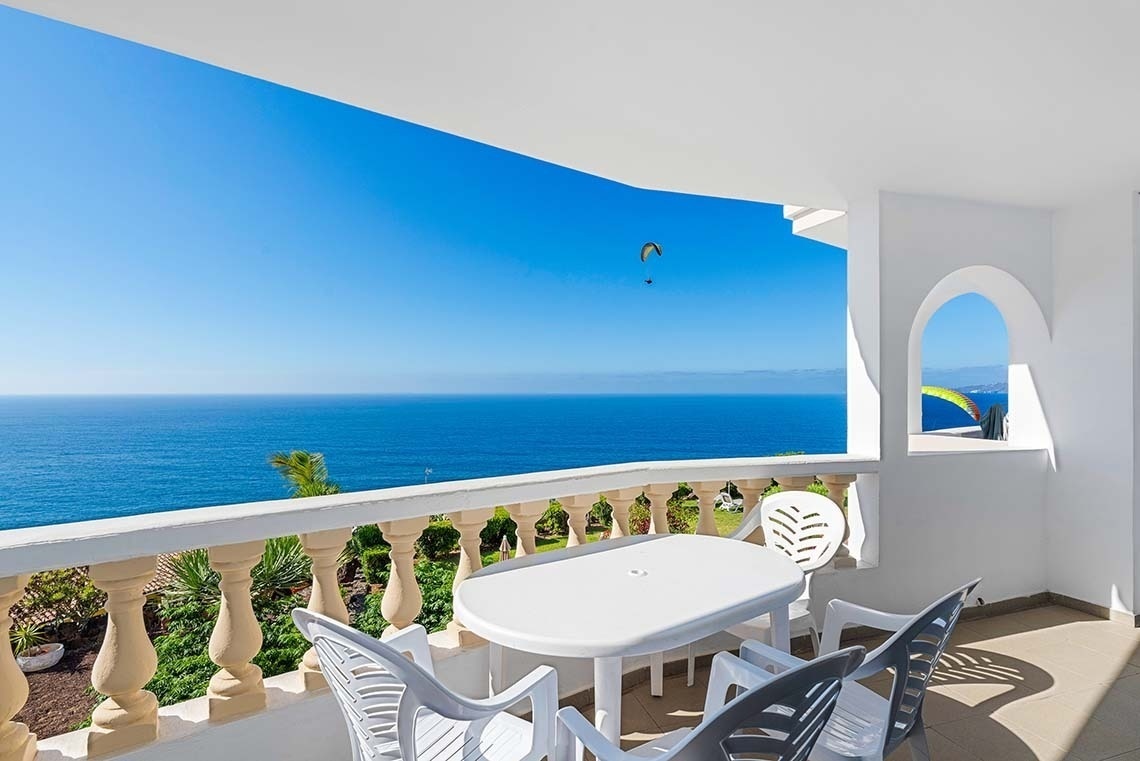 un hamac est assis sous un parapluie sur une terrasse avec vue sur l' océan