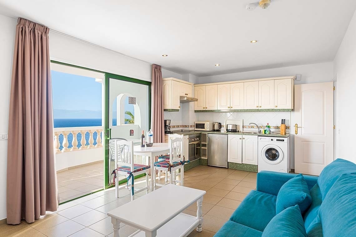 une cuisine avec un canapé bleu et une table blanche